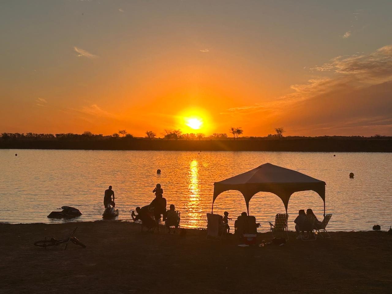 Gente disfrutando el atardecer frente a la laguna